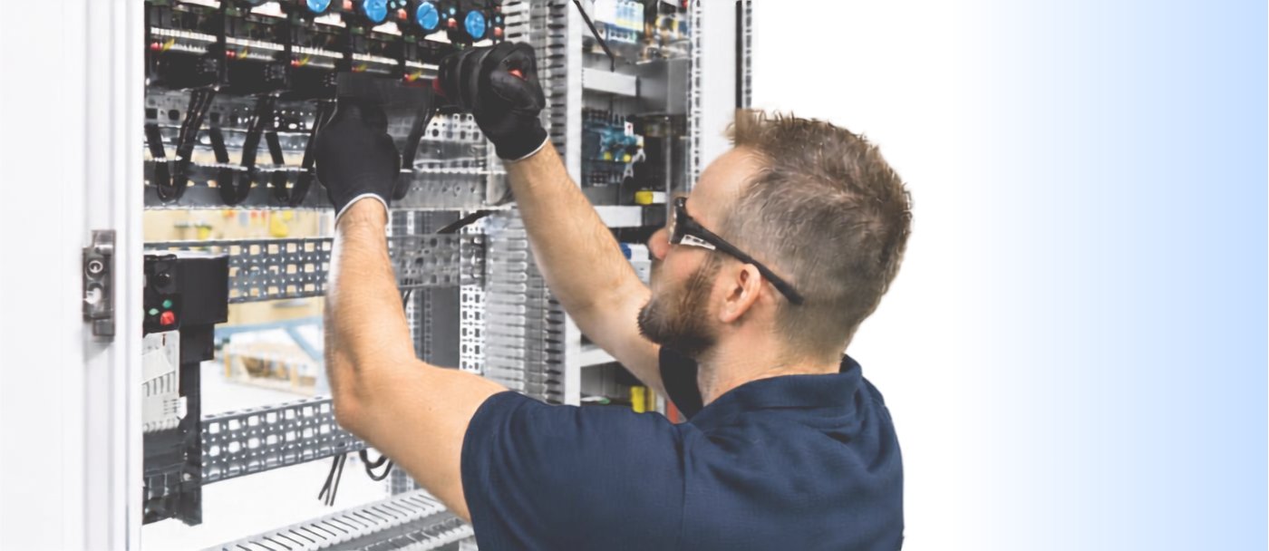 An electrician working inside a control panel.