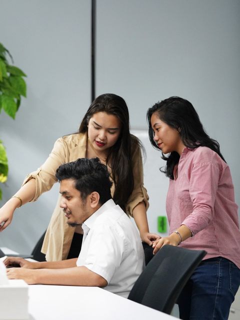 Two team members reviewing work at a colleague’s screen