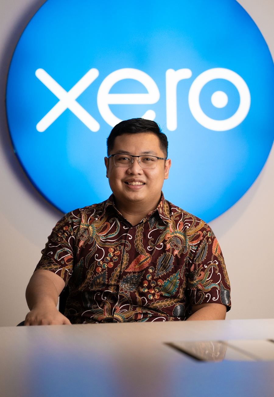 A senior Logiframe accountant in batik in front of the Xero sign.