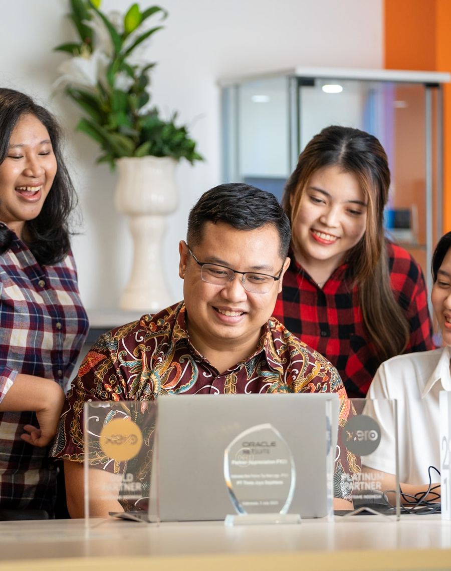 The Logiframe team gathered around a laptop, with Xero and NetSuite partner awards on the desk.