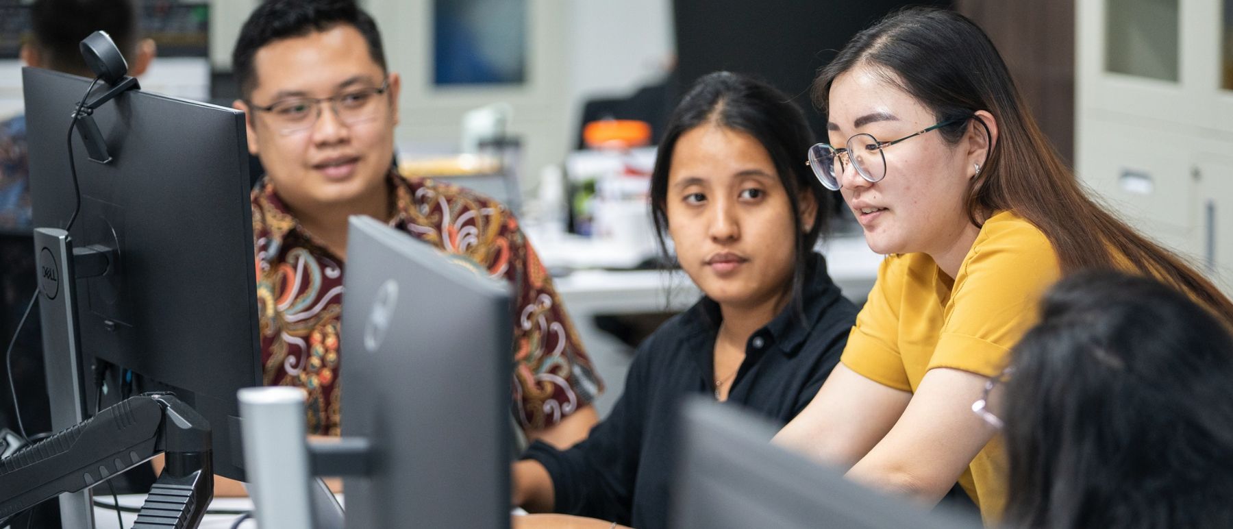 Four members of the Logiframe team reviewing a client's books together at a workstation.